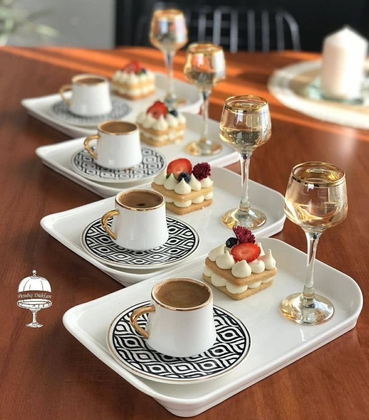 small desserts and wine glasses are sitting on the table with white dishes in front of them