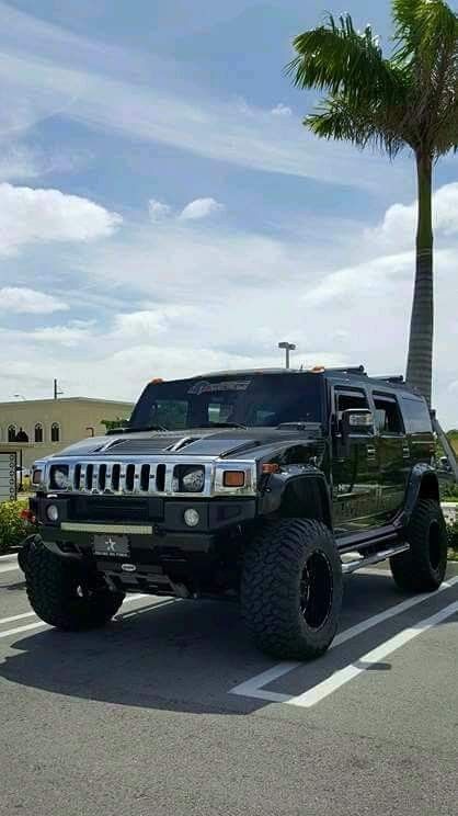 a hummer truck parked in a parking lot next to a palm tree