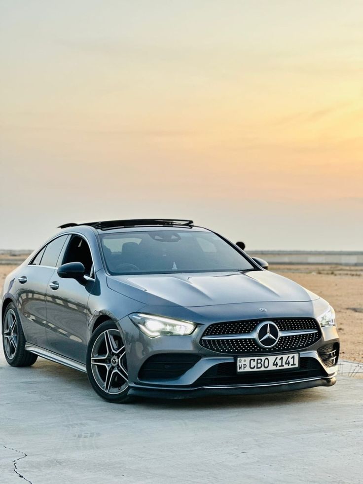 the mercedes benz cla is parked in front of an empty parking lot at sunset