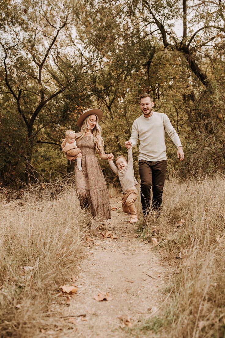 a man and woman walking down a dirt path with their child in the middle of it