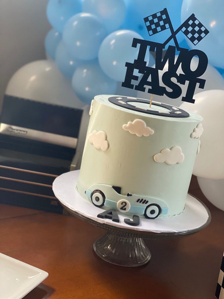 a cake that is sitting on top of a table with some balloons in the background