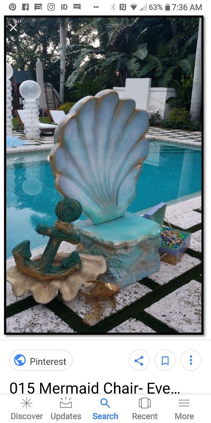 a statue of an anchor and seashell next to a swimming pool