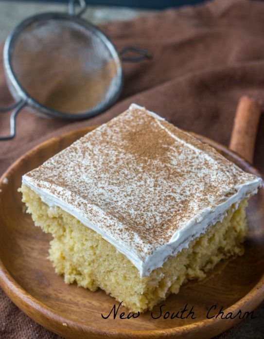 a piece of cake sitting on top of a wooden plate next to a cinnamon stick