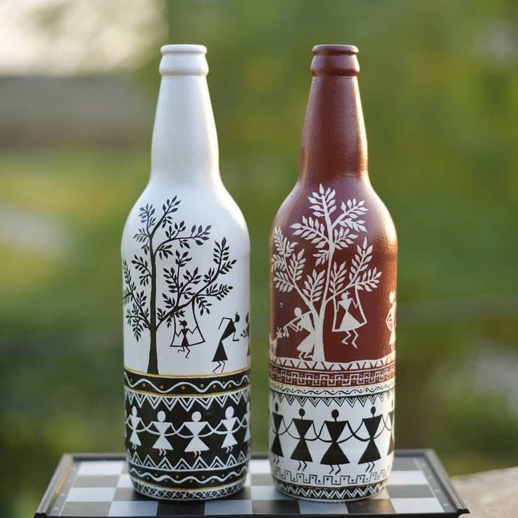 two beer bottles sitting on top of a chess board covered in black and white designs