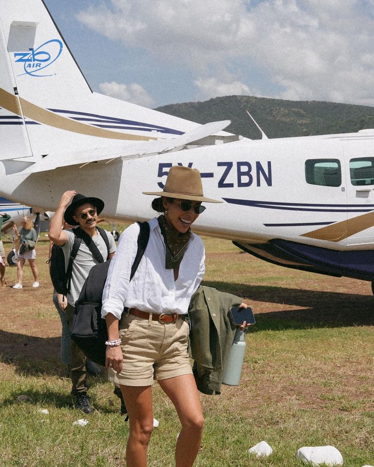 a man standing in front of an airplane on top of a grass covered field next to other people