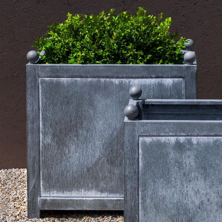 two metal planters sitting next to each other