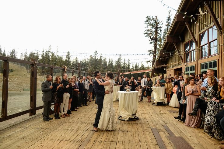 a bride and groom share their first dance on the deck of an outdoor wedding venue