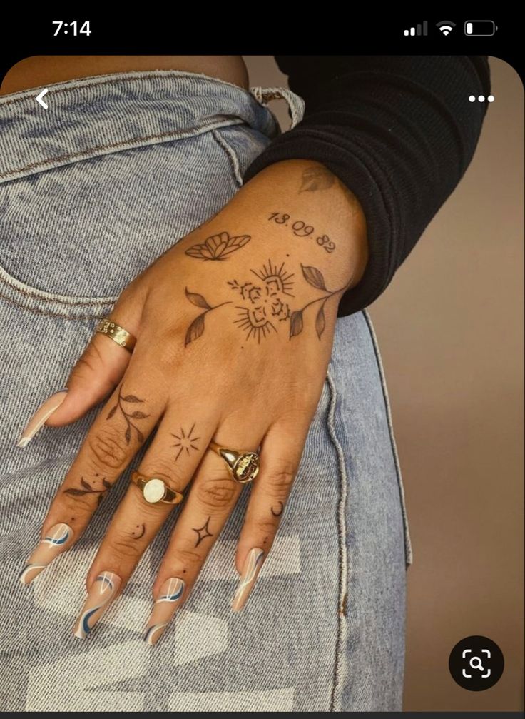 a woman's hand with tattoos on her left arm and two rings on her left wrist