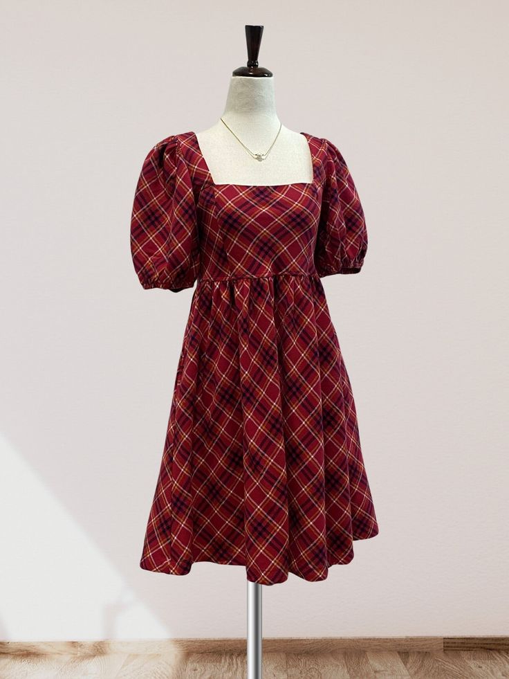 Featuring a checkered plaid print on woven fabric, this mini dress is perfect for the fall and winter months. The square neckline and short puff sleeves add a touch of femininity, while the babydoll waistline and smocking detail on the back provide a comfortable and flattering fit. Complete with a back tie detail and convenient side pockets, this dress is the perfect choice for the holiday season. Square Neck Plaid Dress For Picnic, Fall Plaid Dress With Square Neck, Casual Square Neck Plaid Dress For Fall, Casual Plaid Dress With Square Neck For Fall, Fitted Plaid Dress With Square Neck, Plaid Puff Sleeve Dress For Picnics, Plaid Puff Sleeve Dress For Picnic, Fall Plaid Dress With Short Sleeves, Casual Fitted Plaid Dress With Puff Sleeves