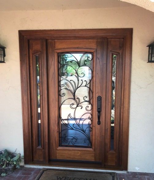 the front door is decorated with glass and wrought iron designs, along with a welcome mat