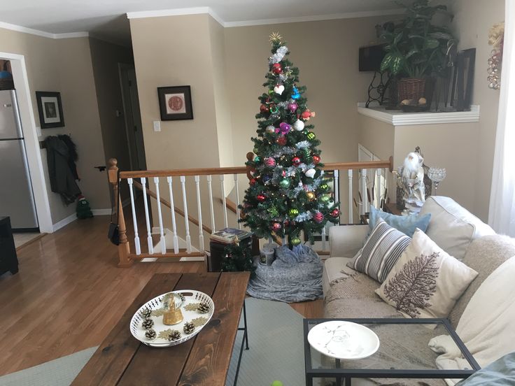 a living room with a christmas tree in the corner and decorations on the coffee table