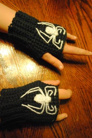 two hands with black and white knitted gloves on top of a wooden table