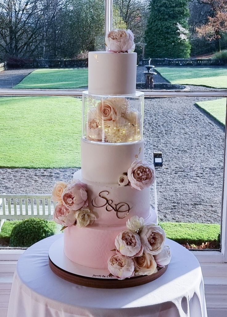 a three tiered cake sitting on top of a table next to a large window