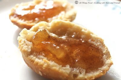 three small pastries sitting on top of a white plate covered in jelly and butter