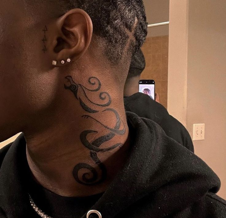 a woman with a tattoo on her neck and behind her ear is looking at the camera