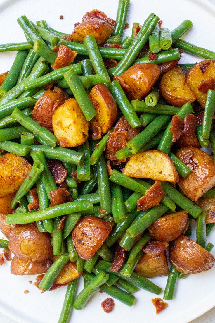 a white plate topped with green beans and potatoes