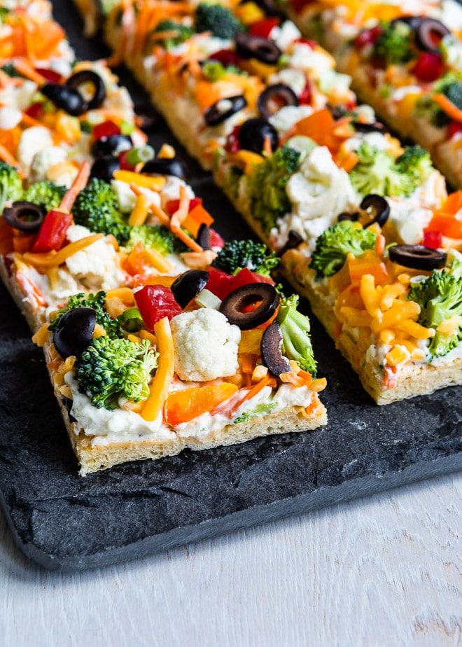 a pizza with broccoli, olives, cheese and other toppings on it