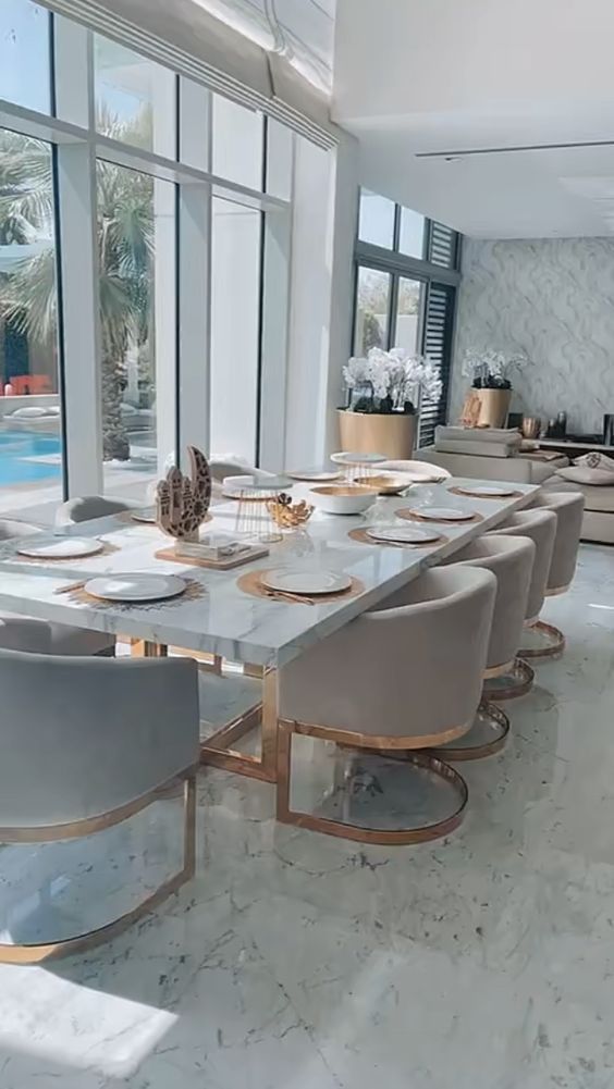 a dining room table with chairs and plates on it in front of a large window