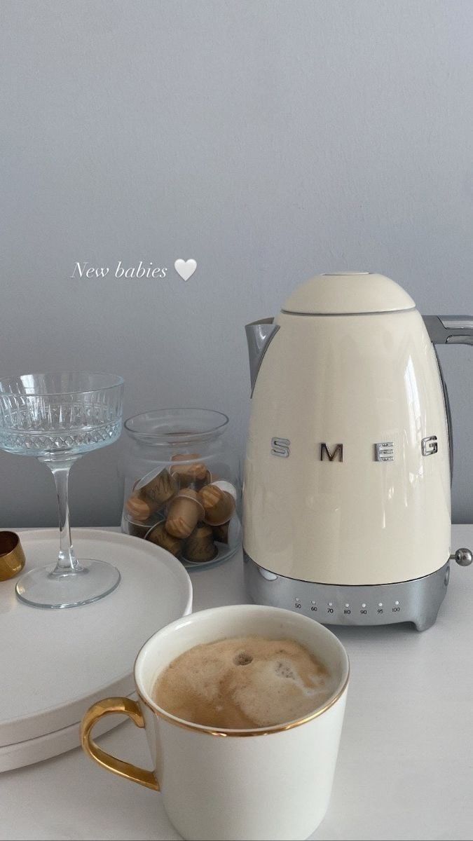 a cup of coffee sitting next to a toaster and some glasses on a table