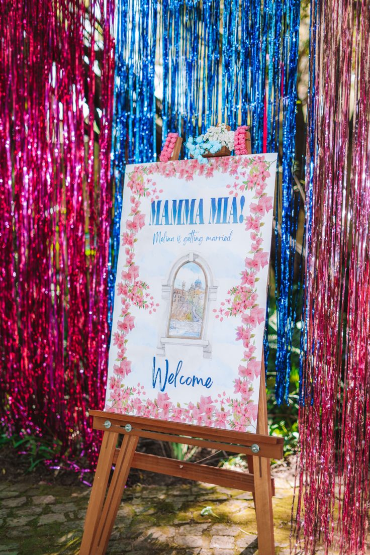 a welcome sign with streamers hanging from it's sides and the words mama mia on it