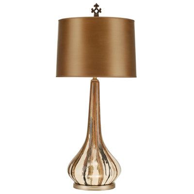 a table lamp with a brown shade on it and a gold base, sitting next to a white wall