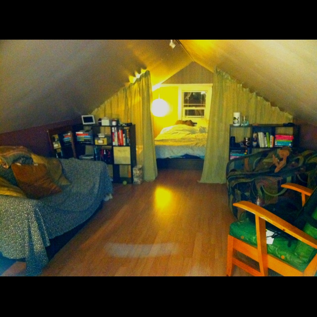 an attic bedroom with wood floors and yellow curtains