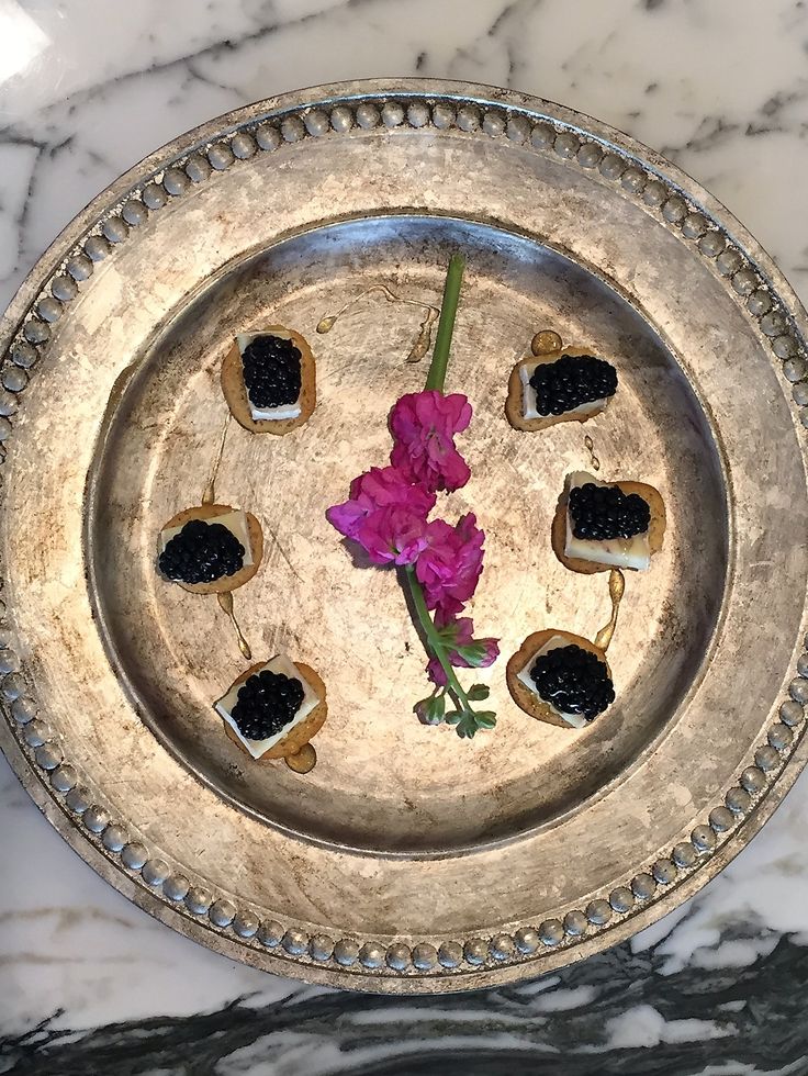 a silver plate topped with small pieces of food on top of a marble countertop