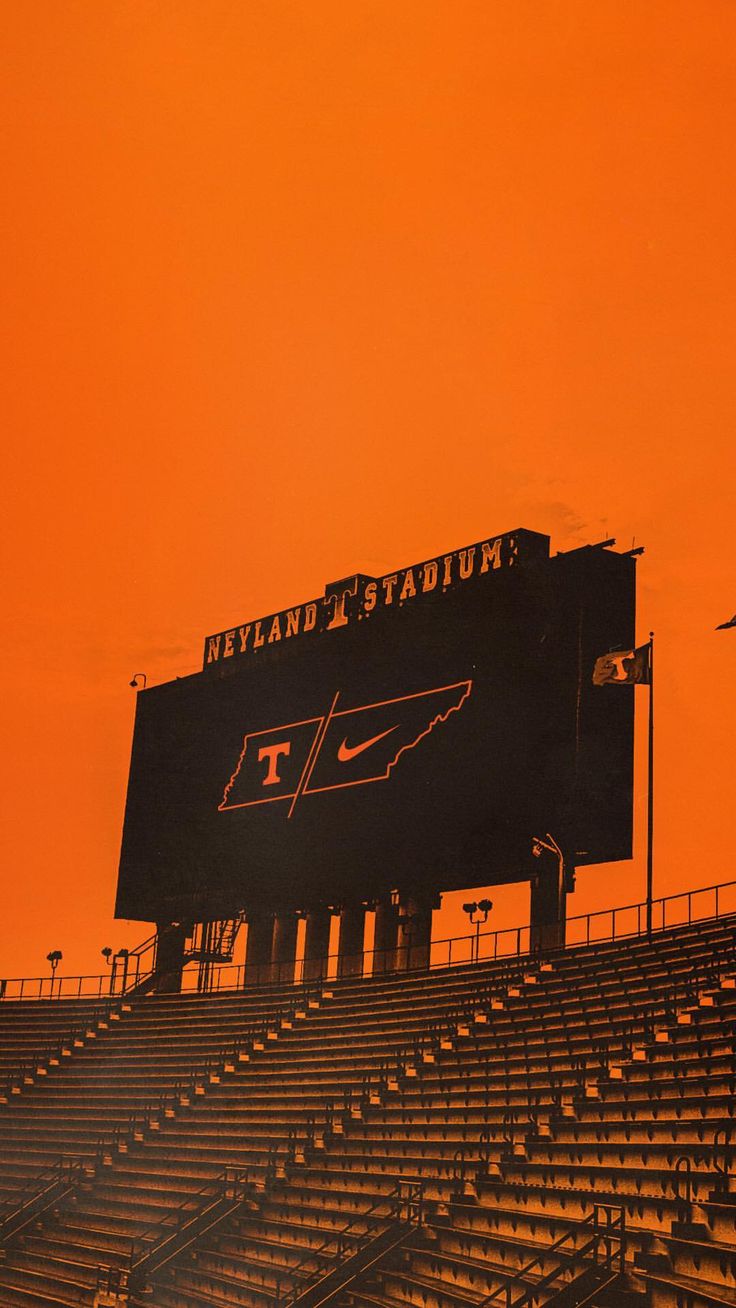 an orange sky over the bleachers and stands at university of tennessee's football stadium