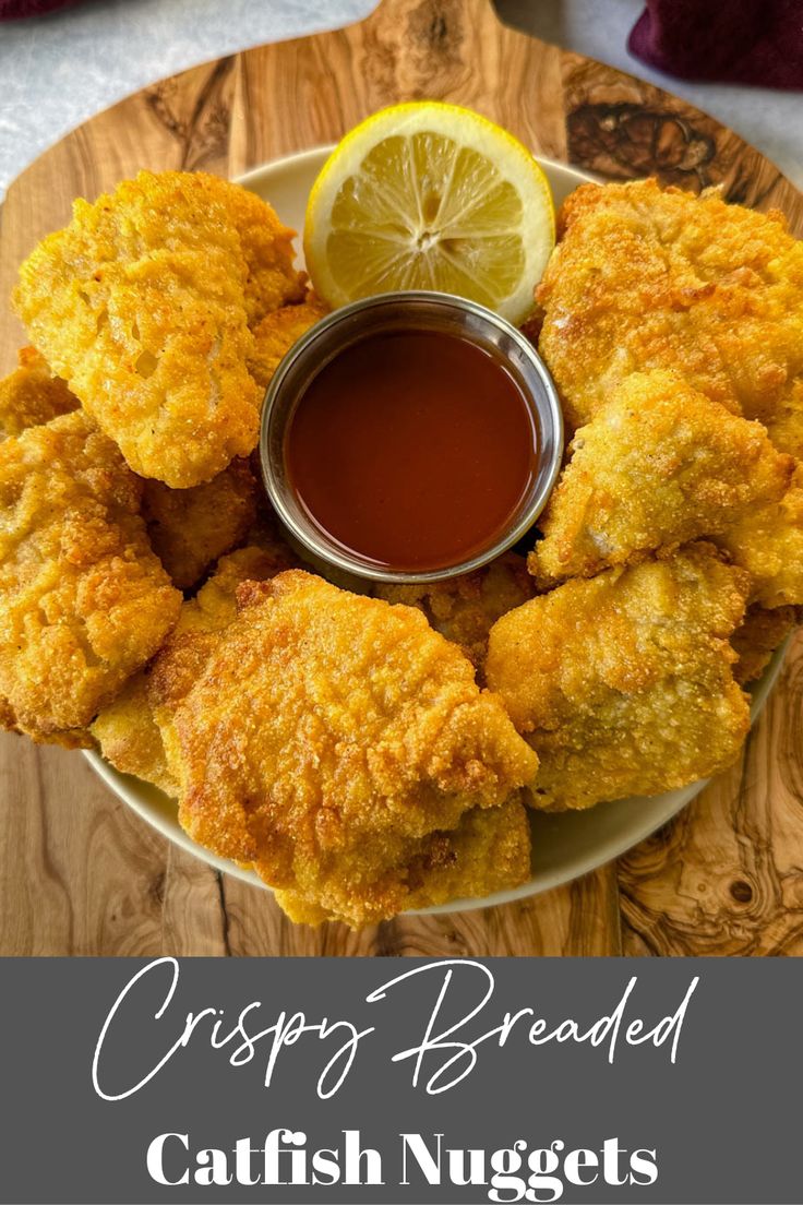 crispy breaded fish nuggets on a plate with dipping sauce and lemon wedges