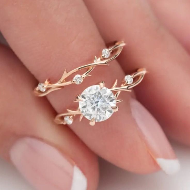 a woman's hand holding an engagement ring with leaves and diamonds on the band