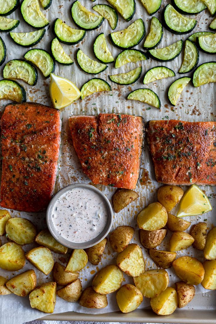 grilled salmon, potatoes and zucchini on a baking sheet with dipping sauce