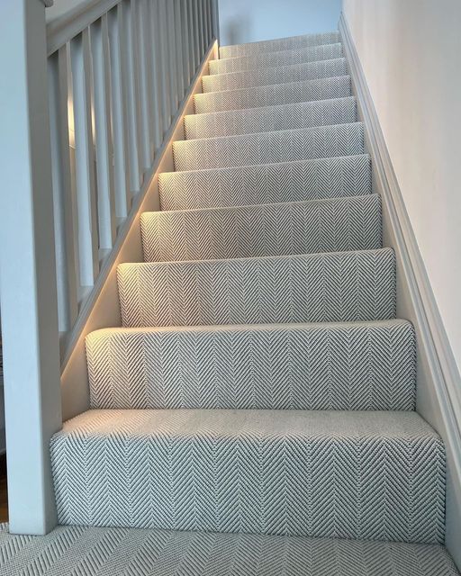 a set of stairs leading up to the second floor with carpeted treads and white handrails