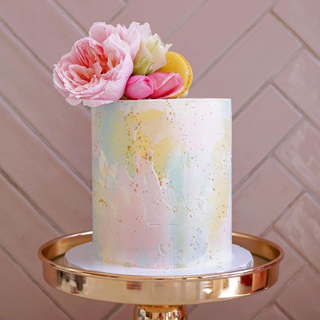 there is a white cake with pink flowers on the top and gold trimmings