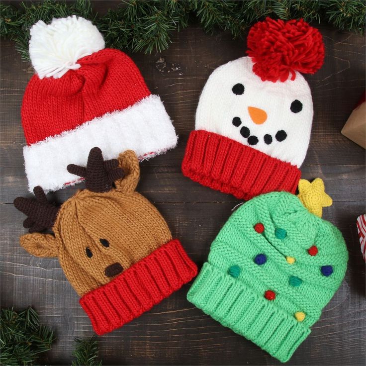 three knitted christmas hats sitting on top of a wooden table