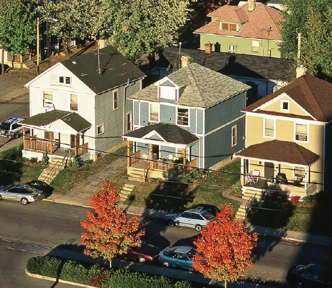 an aerial view of several houses with cars parked on the street in front of them