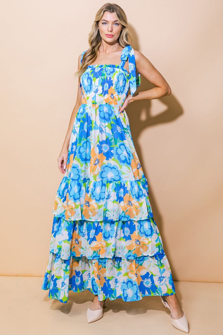 A printed woven maxi dress featuring straight neckline, shoulder tie, smocked bodice and ruffle layered skirt Introducing our NO MATTER WHERE WOVEN MAXI DRESS. This printed masterpiece features a straight neckline, elegant shoulder ties, and a figure-flattering smocked bodice. The ruffle layered skirt adds a touch of whimsy and movement to this exclusive dress. Perfect for any occasion, this dress will make you stand out with its sophisticated and luxurious design. Details:Self : 100% PolyesterL Spring Vacation Tiered Dress With Square Neck, Vacation Maxi Dress With Tie Straps And Straight Neckline, Summer Tiered Printed Maxi Dress, Beach Maxi Dress With Smocked Back And Square Neck, Tiered Maxi Dress With Smocked Bodice For Garden Party, Summer Tiered Maxi Dress With Print, Floral Print Maxi Dress With Ruffled Straps For Vacation, Blue Beach Dress With Straight Neckline, Blue Dress With Straight Neckline For Beach