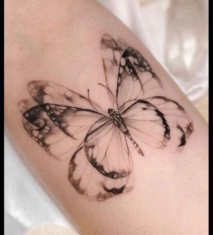 a black and white butterfly tattoo on the arm