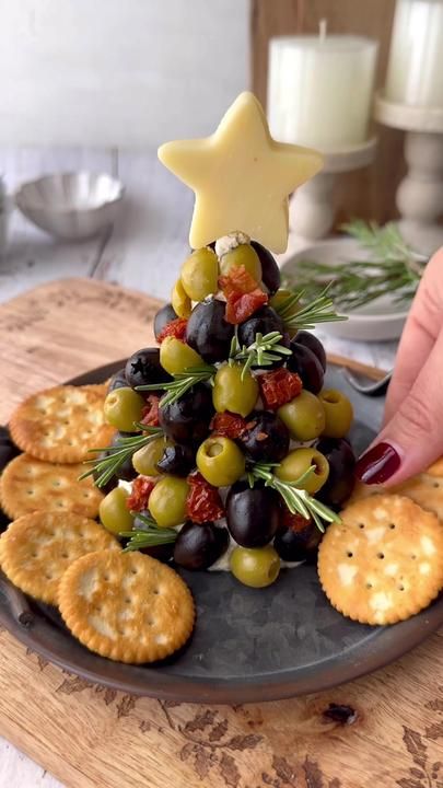 a christmas tree made out of crackers and olives on a plate with a star decoration