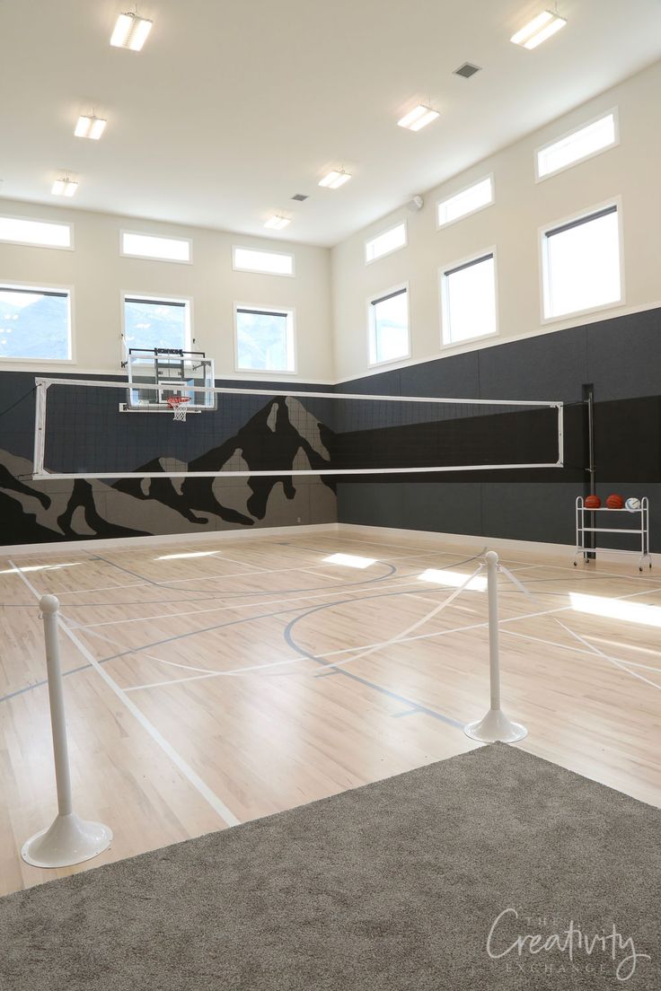 an indoor basketball court with a net in the middle and several windows on the side