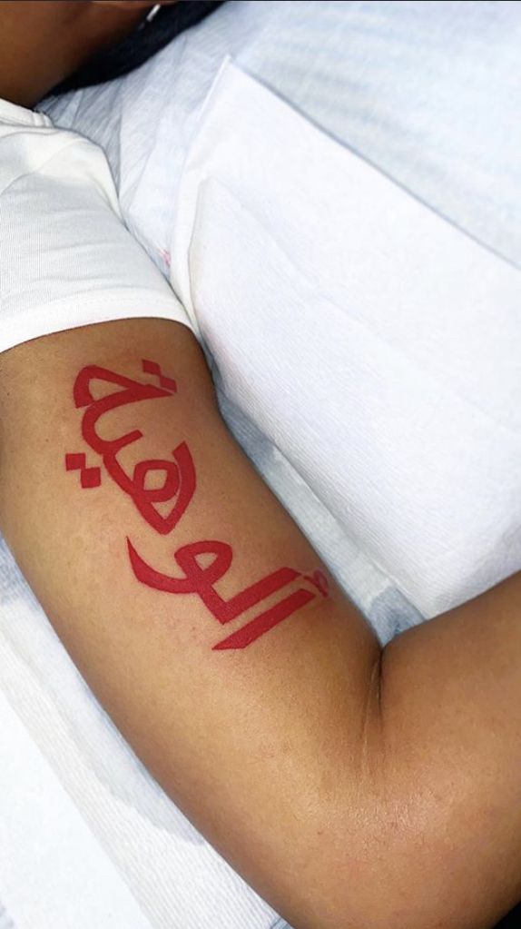 a person laying in bed with a tattoo on their arm and the word relax written across it