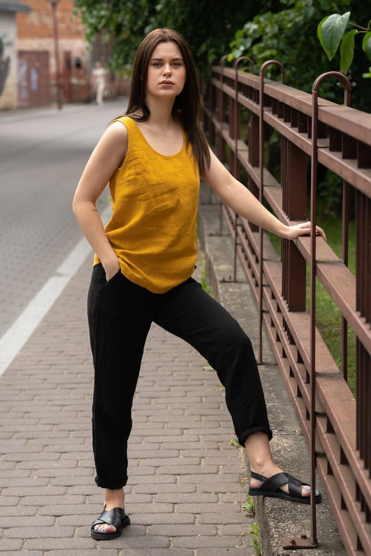 A young woman posing outside in the city street wearing spicy yellow linen blouse and pure black linen pants dakota. Spring Yoga Tank Top With Relaxed Fit, Comfortable Relaxed Fit Sleeveless Tank Top, Relaxed Fit Tops For Warm Weather, Spring Casual Yoga Camisole, Casual Spring Yoga Camisole, Casual Yoga Camisole For Spring, Comfortable Sleeveless Cotton Tank Top, Comfortable Everyday Sleeveless Tank Top, Summer Athleisure Camisole Tank Top