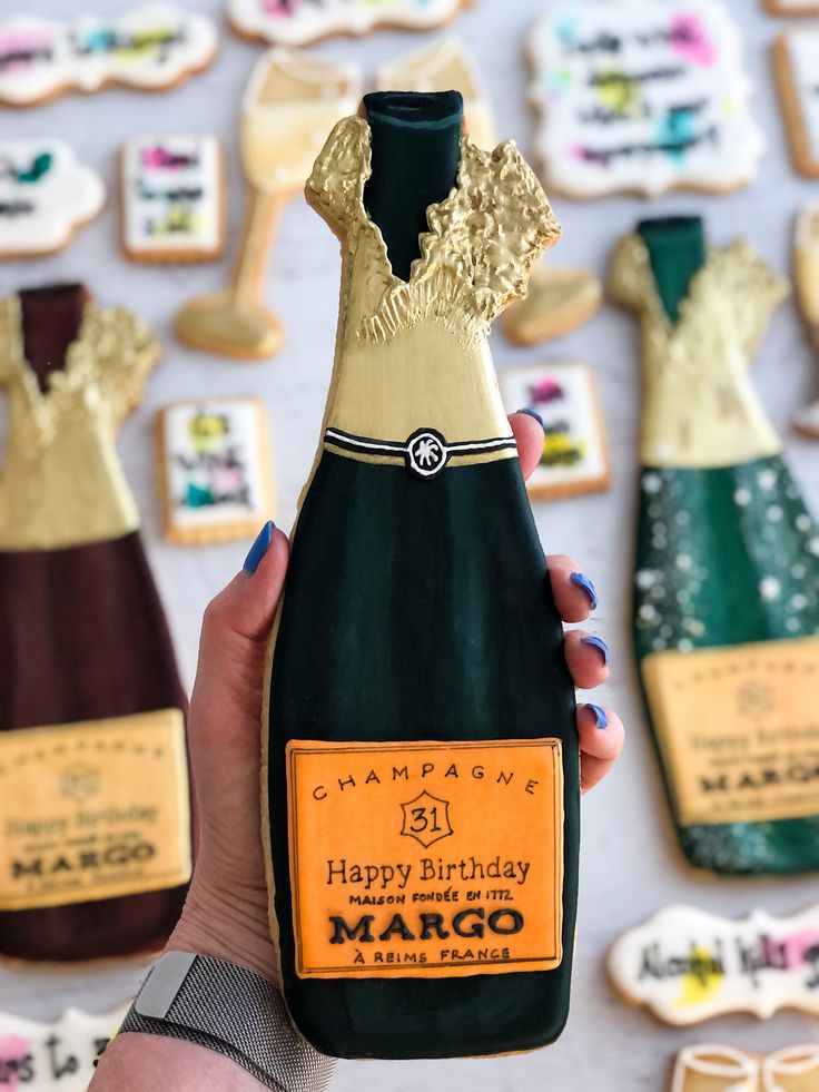 a woman holding up a bottle of champagne in front of cookies and cookies on the table