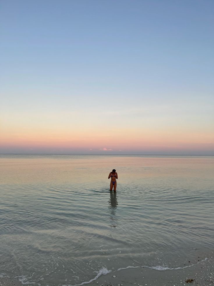 a person standing in the ocean at sunset