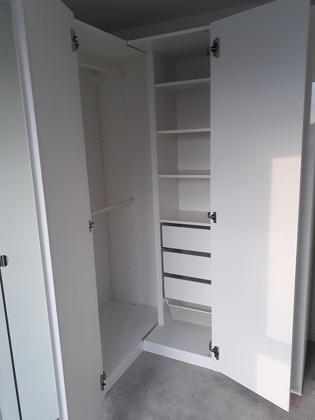 an empty closet is shown with white walls and shelving unit in the corner between two doors