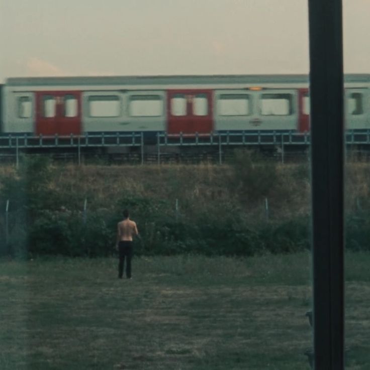 a man standing in front of a train on the tracks with his back to the camera