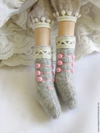 two pairs of socks with pink buttons and laces on them, sitting next to a white dress