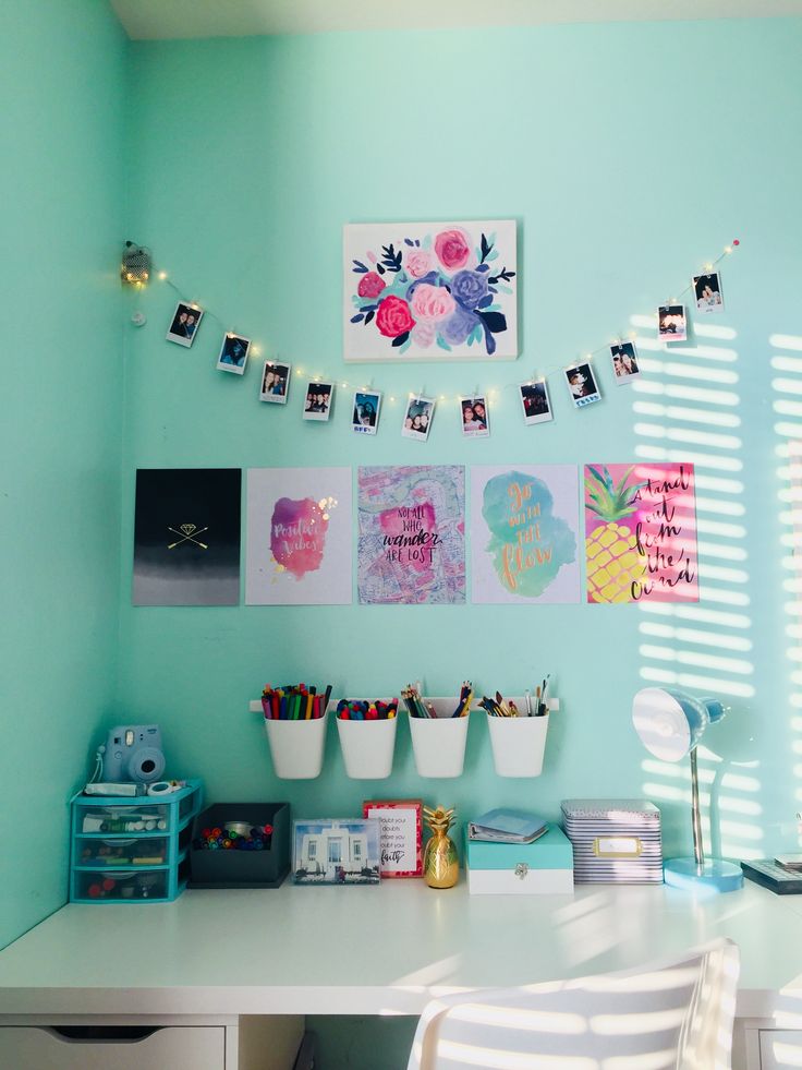 a white desk topped with lots of drawers under a light blue wall covered in pictures