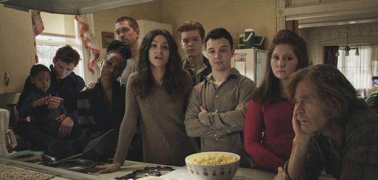 a group of people standing in front of a counter with a bowl of food on it