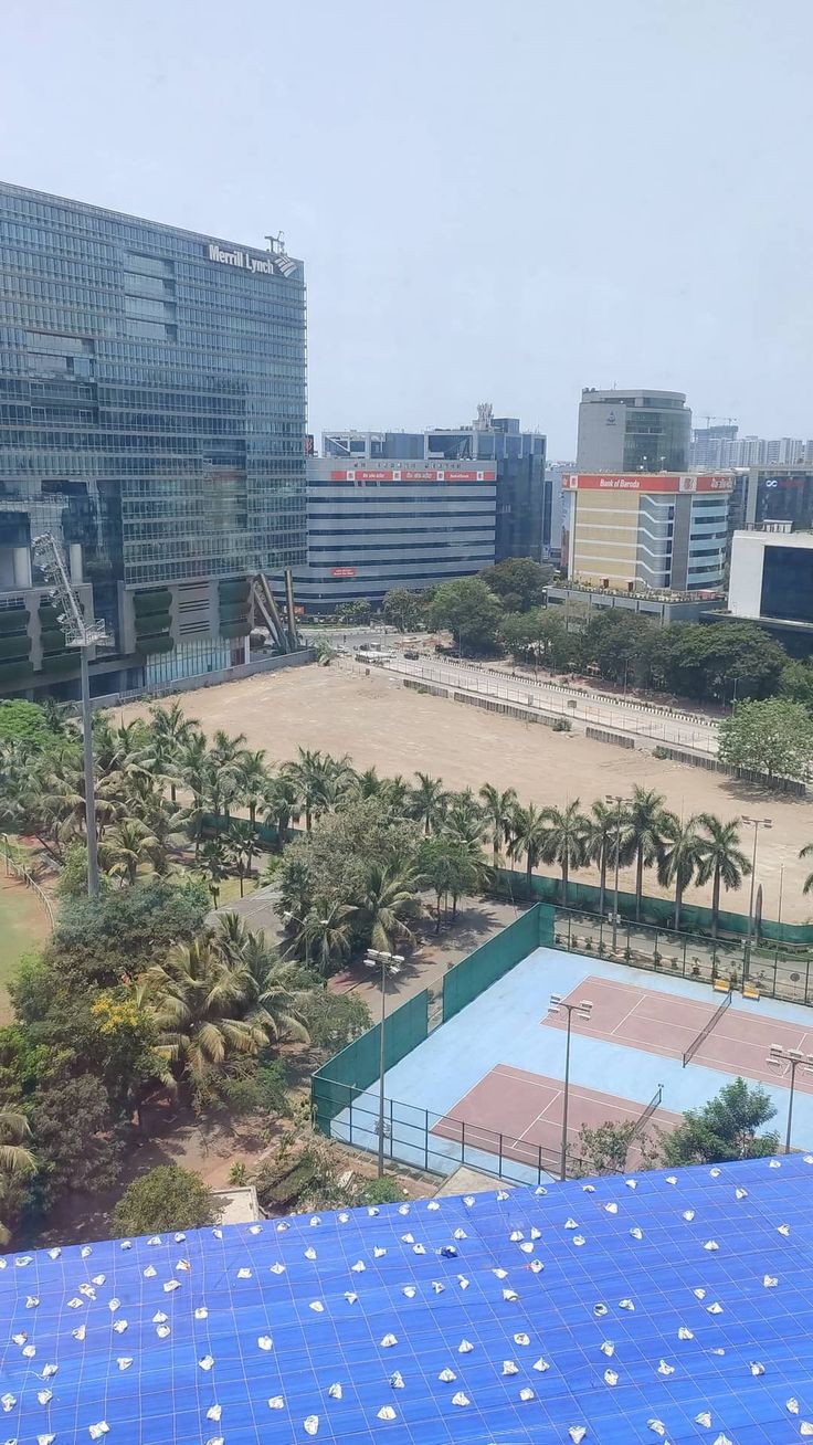 an aerial view of a tennis court in the middle of a city with palm trees