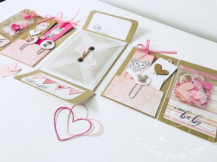 some cards are laying on a table with pink and white hearts around them, including two heart shaped pins